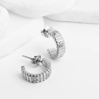 Silver hoop earrings with embedded stones on a white background