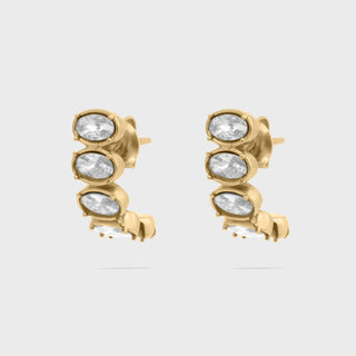 Gold Oval Stone Huggie Earrings with clear gemstones on a light gray background