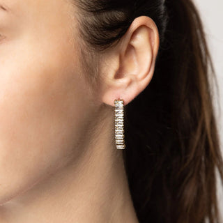 Close-up of an ear wearing a silver hoop earring with a blurred background