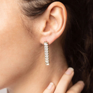 Close-up of an ear wearing a diamond earring with a hand adjusting it.