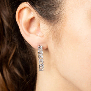 Close-up of an ear wearing a silver hoop earring with dark hair.