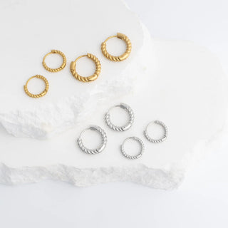 Set of gold and silver hoop earrings on a marble surface