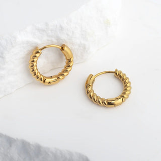 Gold hoop earrings on a white surface