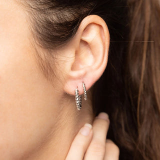Close-up of an ear wearing a silver hoop earring with a blurred background