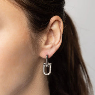 Close-up of an ear wearing a silver earring with a minimal background