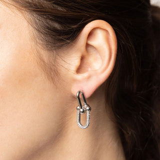 Close-up of an ear wearing a silver earring with a U-shaped design.