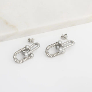 Pair of silver earrings with pearls on a white surface