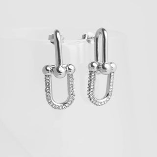 Silver U-shaped earrings with clear stones on a light gray background