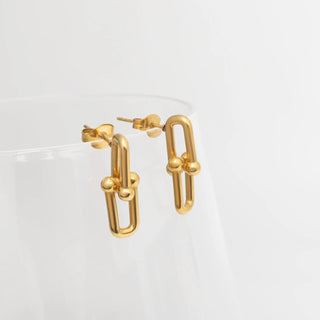 Gold hoop earrings on a clear stand against a white background