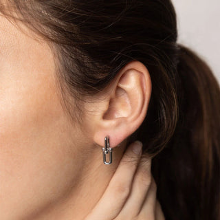 Close-up of an ear wearing a silver hoop earring with a blurred background
