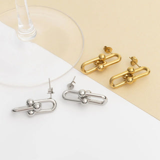 Gold and silver earrings on a white and beige background
