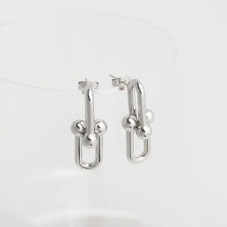 Silver hoop earrings with spherical accents on a light gray background