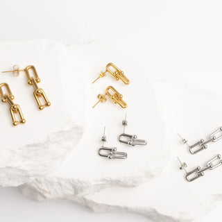 Gold and silver earrings on a white marble surface