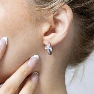 Close-up of an ear wearing a silver cross earring.