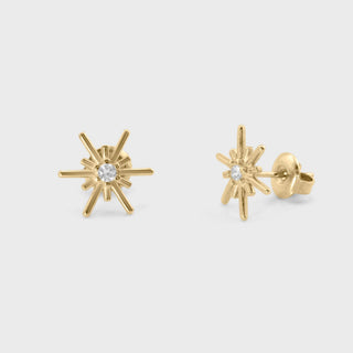 Gold firework earrings with clear gemstones on a light gray background