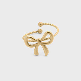 Gold bow-shaped ring on a light gray background