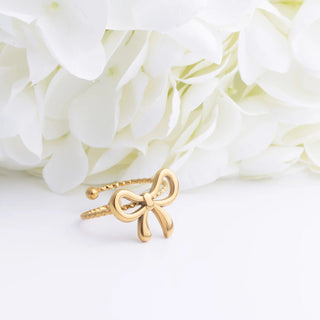 Gold bow-shaped ring on a white floral background