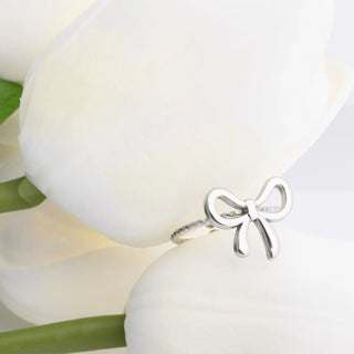 Silver bow-shaped ring on a white flower background