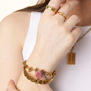Gold jewelry including a bracelet, ring, and necklace on a person's wrist.