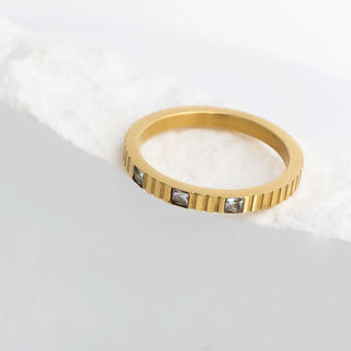 Gold ring with embedded diamonds on a light gray background