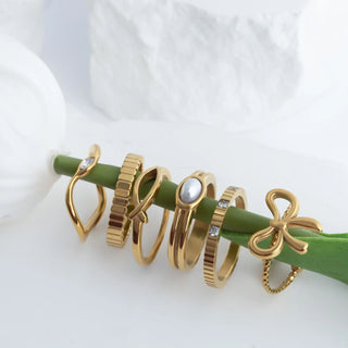 Set of gold rings on a green stick against a white background