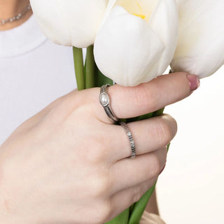 Hand holding white tulips wearing two rings on a blurred background
