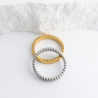 Two rings, one gold and one silver, on a white fabric background