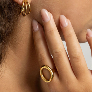 Close-up of a hand wearing a gold ring with a light grey background