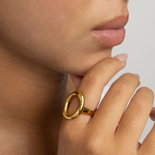Close-up of a hand wearing a gold ring with a plain background