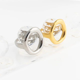 Gold and silver oval rings on a clear ring display on a white background