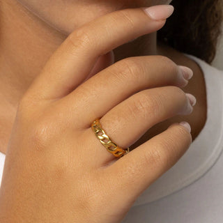 Close-up of a hand wearing a gold ring with a blurred background