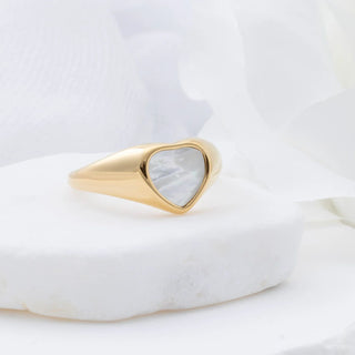 Gold MOP ring with a heart-shaped pearl on a white marble surface