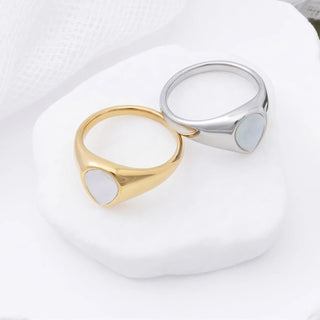 Gold and silver rings with a MOP on a white surface