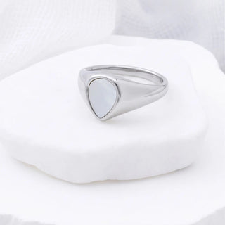 Silver signet ring on a white stone with a white background