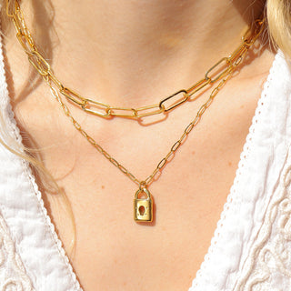 Gold chain necklace with a lock pendant worn by a person