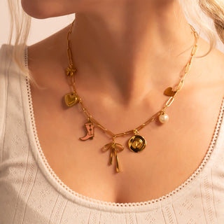 Gold necklace with charms on a person wearing a white top