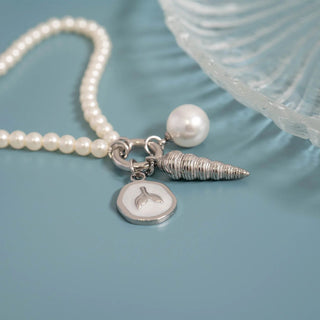 Pearl necklace with silver charms on a light blue background