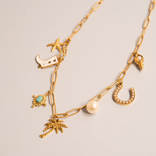 Gold chain necklace with various western charms including the Turquoise Compass Charm on a light gray background