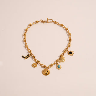 Gold charm hardware necklace with various charms including the Turquoise Tear Drop Charm on a light beige  background