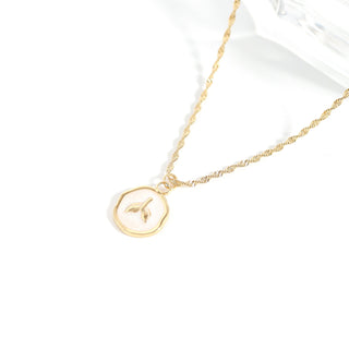 Gold necklace with a circular pendant on a white background
