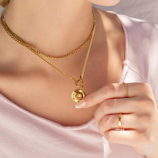 Gold necklace with a cowboy hat  pendant worn by a person, with a close-up of the jewelry.