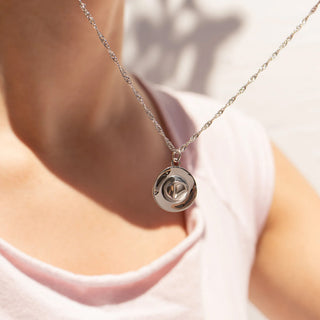 Silver necklace with a cowboy hat  pendant worn by a person