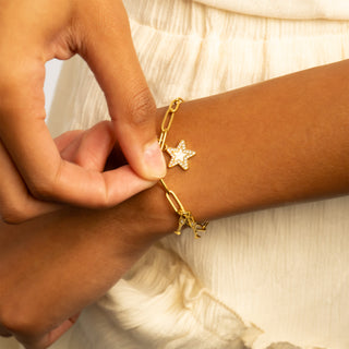 Gold bracelet with star charm being worn on a wrist