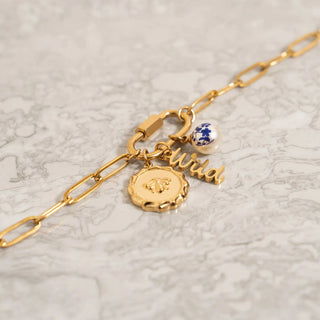 Gold bracelet with charms on a light gray background