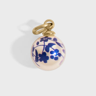 Gold pendant with a white background and blue floral design