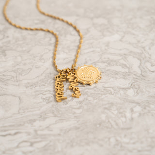 Gold necklace with a pendant on a textured beige surface