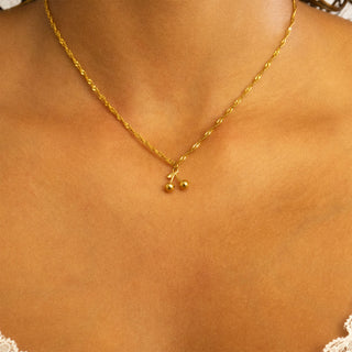 Gold necklace with a small pendant on a person's neck