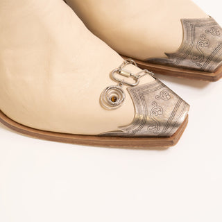 Beige shoe with decorative silver heel and white background