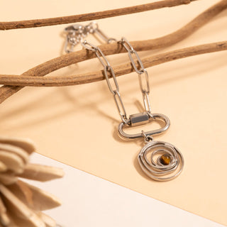 Silver chain necklace with a circular pendant on a beige background