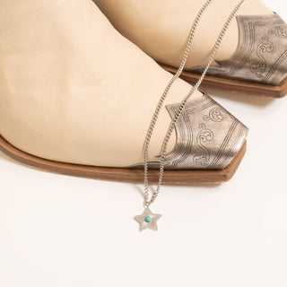 Necklace with a star pendant on a beige boot with intricate design.
